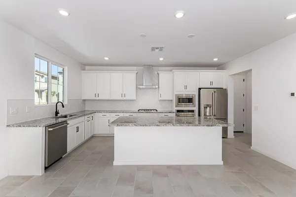 a large kitchen with stainless steel appliances kitchen island a large counter top and a stove top oven