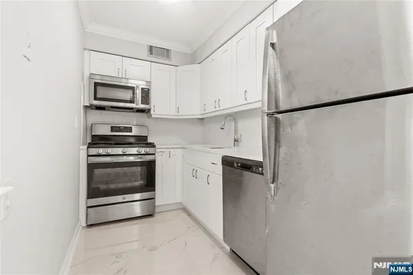 a kitchen with stainless steel appliances white cabinets and a stove top oven