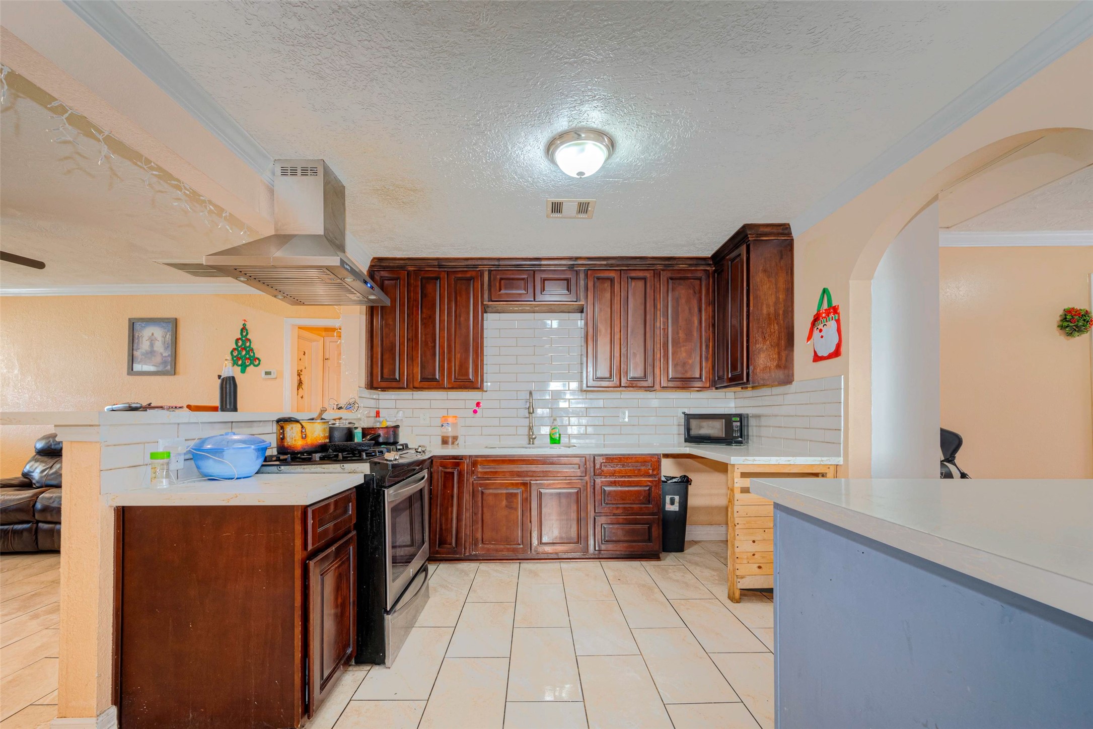 This kitchen offers quarts countertops, subway tile wood cabinets and exhaust fan