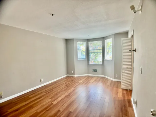 a view of an empty room with wooden floor and a window