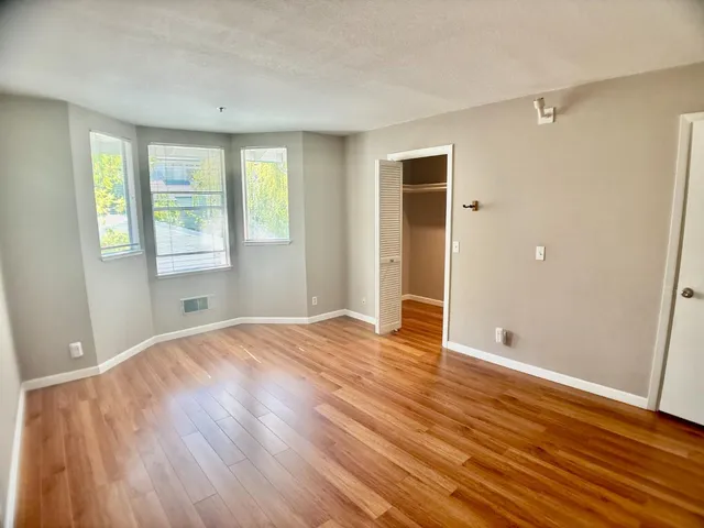 a view of an empty room with wooden floor and a window