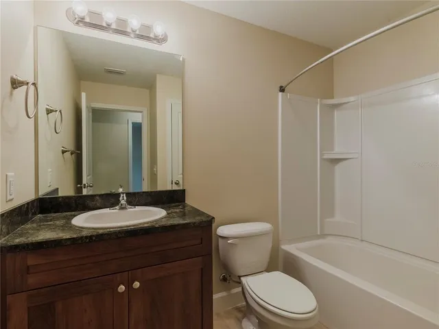 a bathroom with a granite countertop sink toilet a mirror and shower