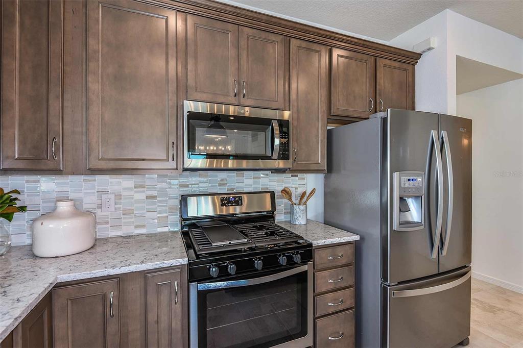 2364 Daisy Tree Road St. Cloud, FL 34771 - Photo 5 of 31 a kitchen with granite countertop a stove microwave and refrigerator