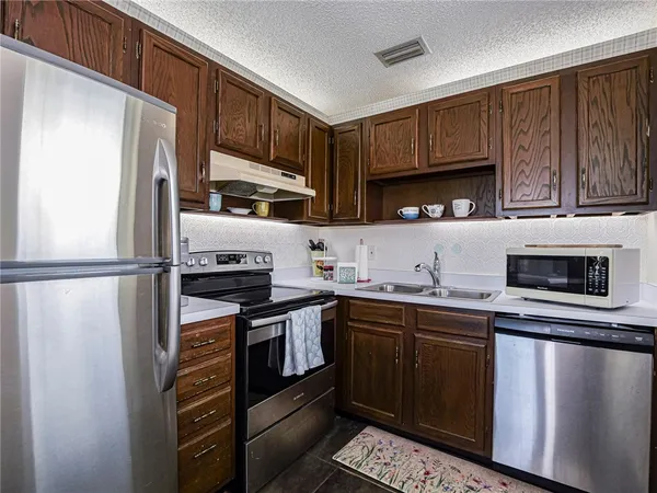 a kitchen with stainless steel appliances a sink a stove a microwave and wooden cabinets