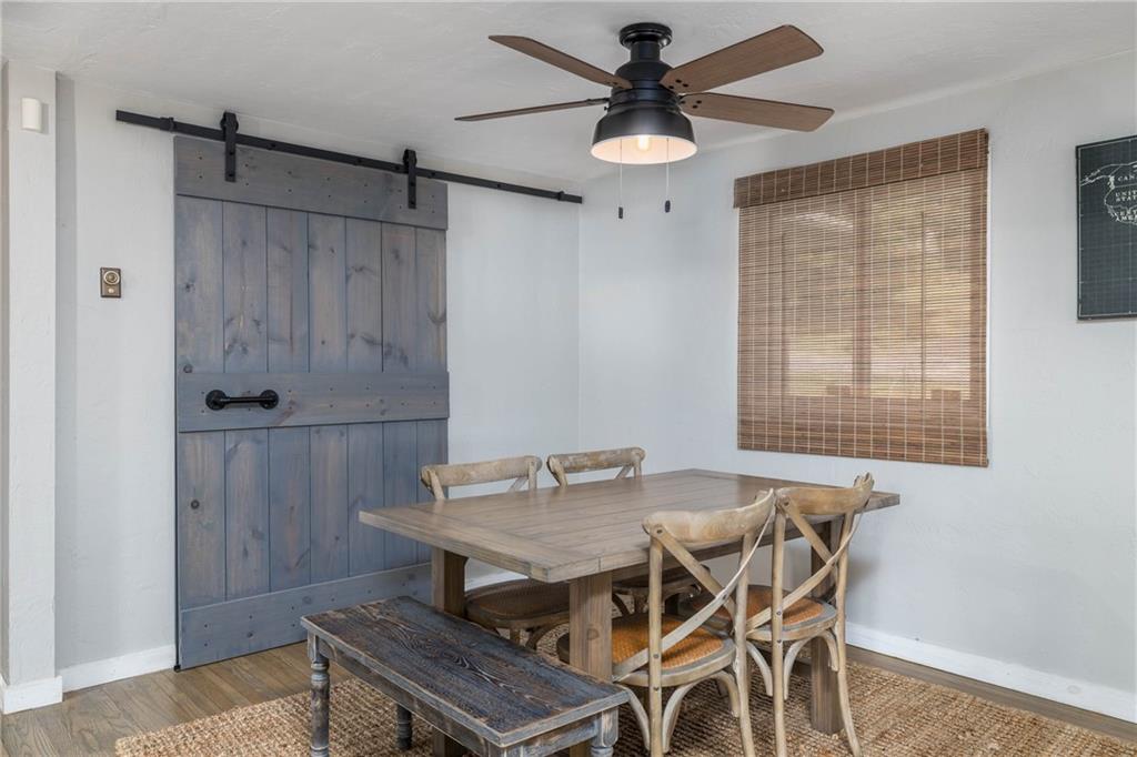 The dining area is accented with an overhead ceiling fan and "barn doors" covering the pantry.