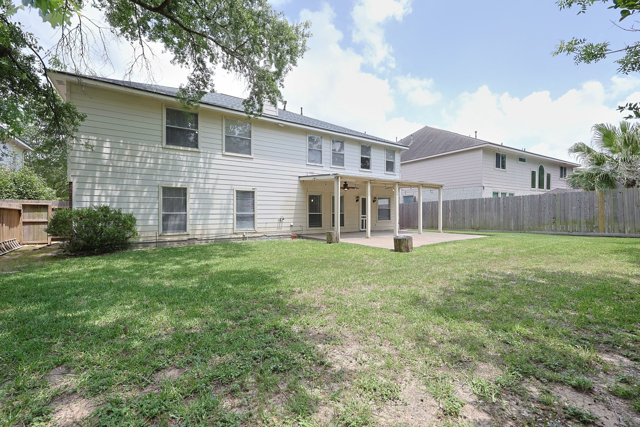 23019 Eastgate Village Drive Spring, TX 77373 - Photo 39 of 46 Spacious backyard with a covered patio, perfect for outdoor activities. The two-story home features multiple windows for natural light, and the yard is fenced for privacy, offering a great space for relaxation and gatherings.