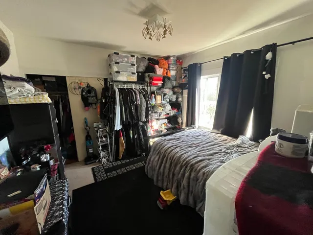 a bedroom with a bed a flat screen tv and a window