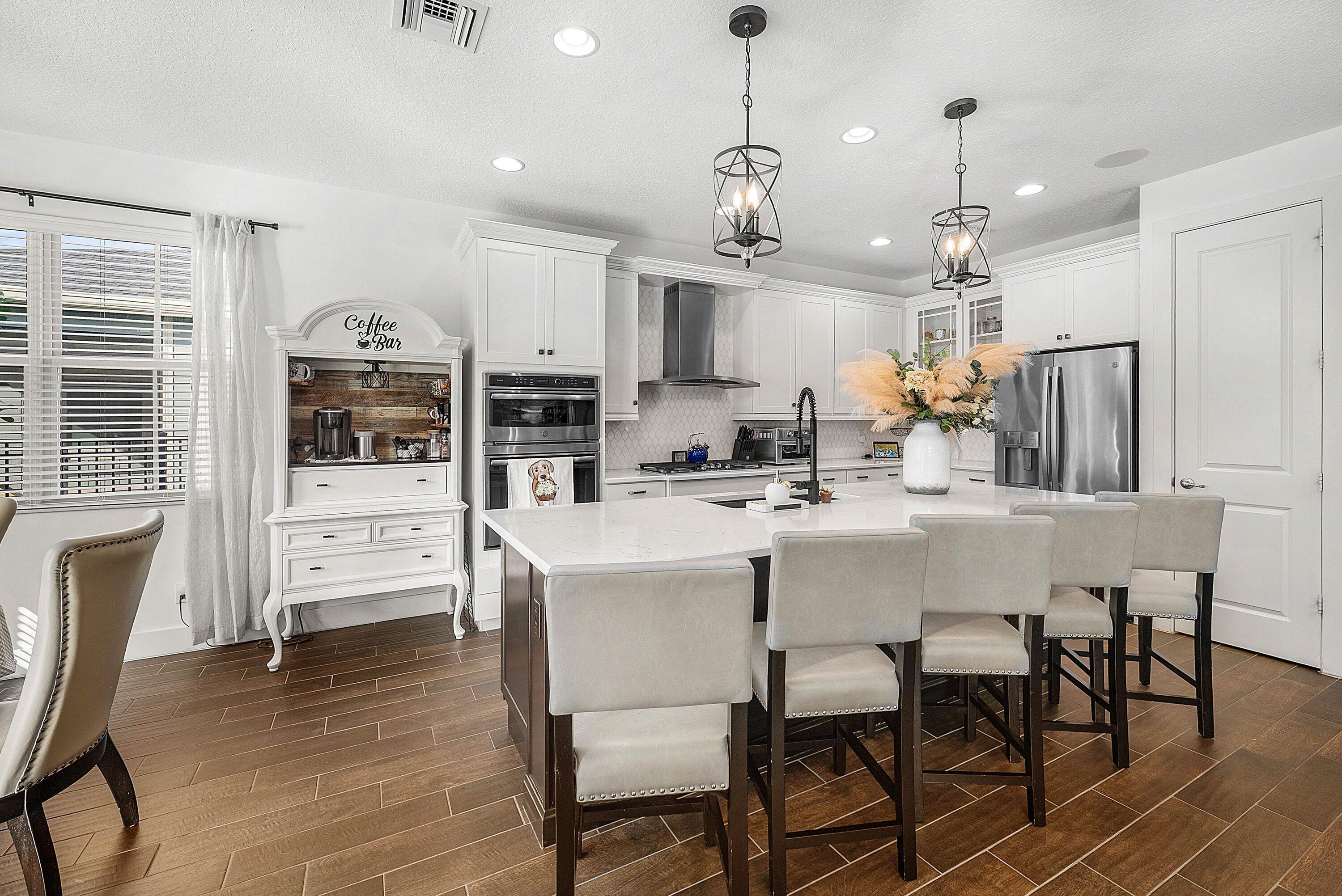 1107 Timber Reap Trail Loxahatchee, FL 33470 - Photo 10 of 83 a kitchen with stainless steel appliances kitchen island granite countertop a dining table chairs refrigerator and cabinets