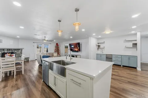 a kitchen that has a lot of cabinets a sink and wooden floor