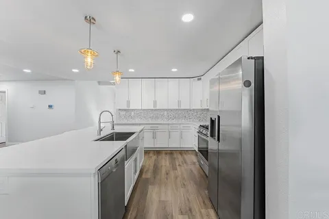 a kitchen with a sink chandelier and wooden floor