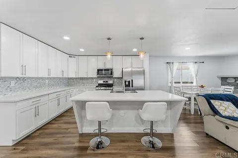 a kitchen with kitchen island a stove a sink a refrigerator and chairs
