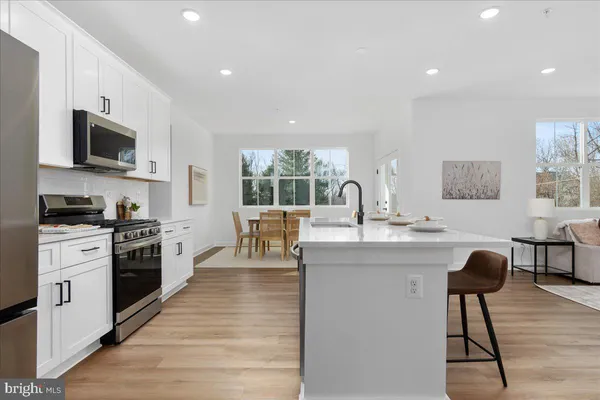 a kitchen with stainless steel appliances kitchen island granite countertop a stove top oven a sink a dining table and chairs with wooden floor