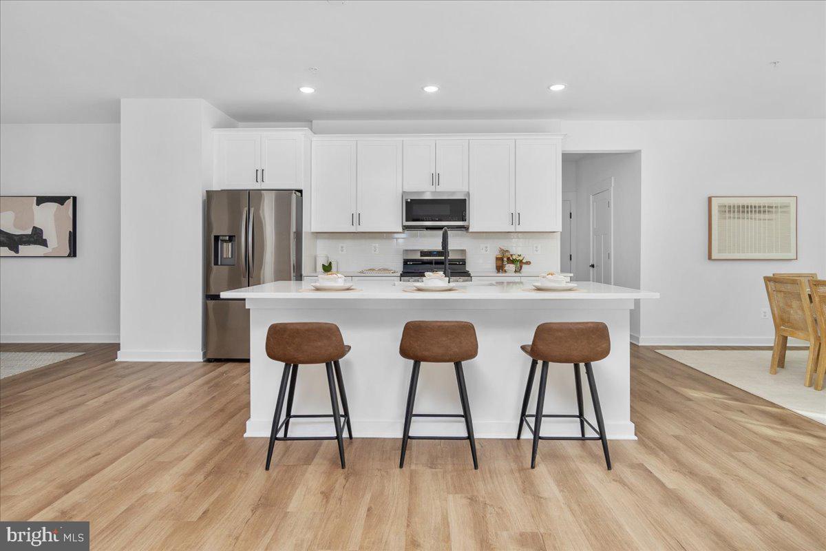 641 Swallowtail Drive Frederick, MD 21703 - Photo 16 of 52 a kitchen with stainless steel appliances kitchen island granite countertop a dining table chairs refrigerator and sink