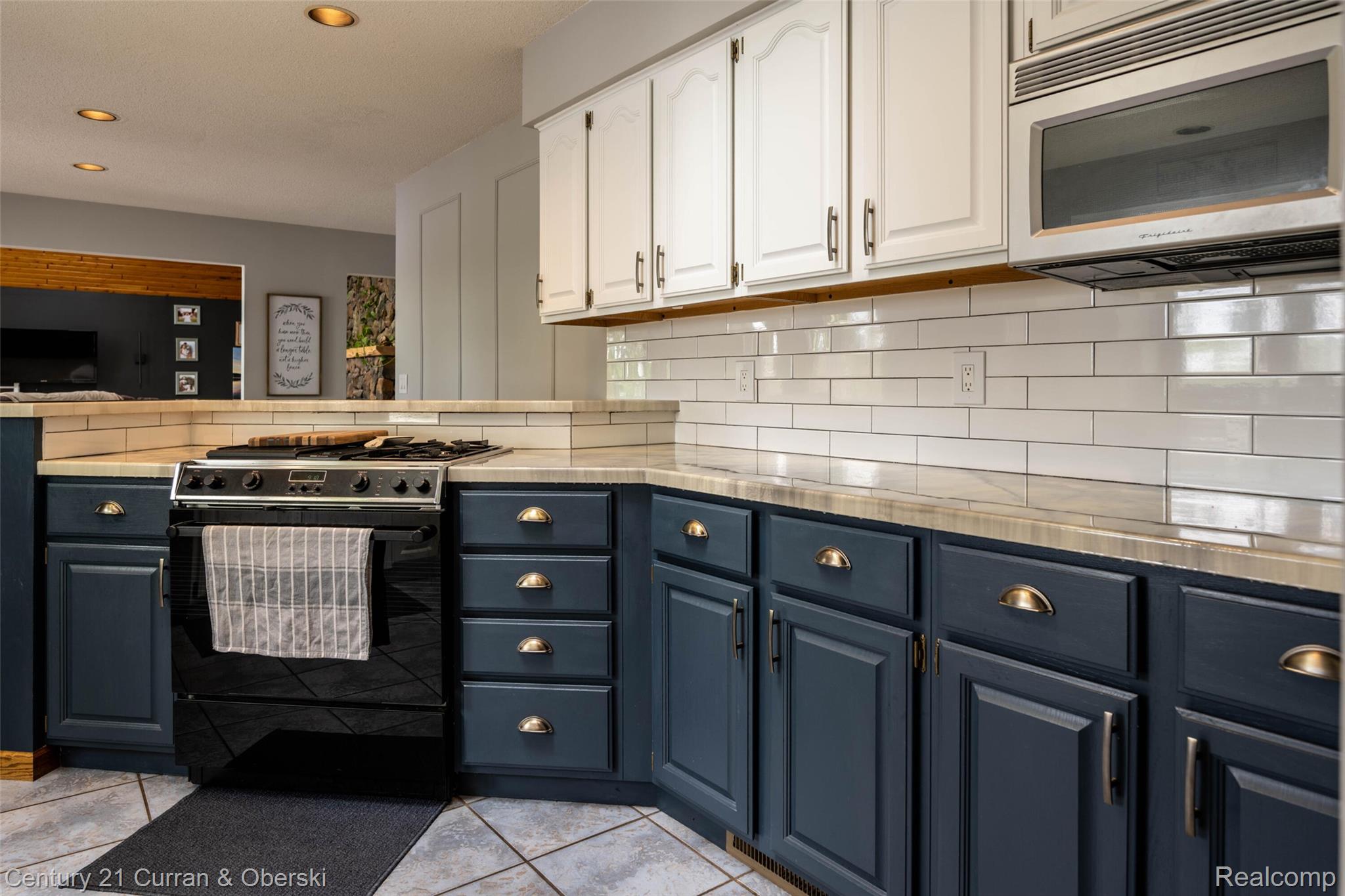 8775 Winding Rdg Drive Millersburg, MI 49759 - Photo 16 of 53 Kitchen featuring two-tone cabinetry with white upper and dark lower cabinets, a black range, and white subway tile backsplash
