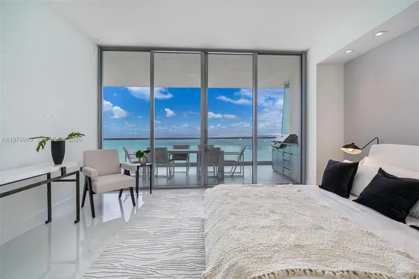 a bedroom with a bed and with a large window