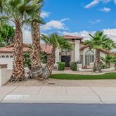 a view of a house with a yard and table and chairs under an umbrella