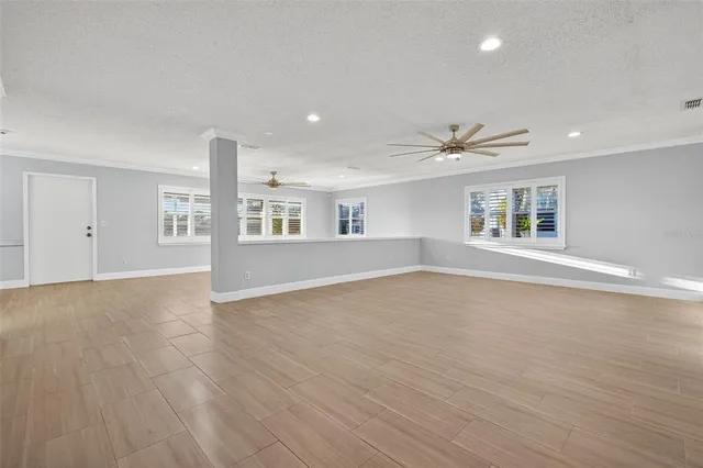 a view of an empty room with a window and wooden floor