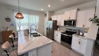 a kitchen with kitchen island a counter space a stove a sink a refrigerator and furniture