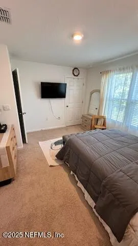a bedroom with a bed a flat screen tv and a large window