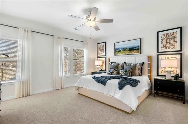 a spacious bedroom with a bed a couch and large window