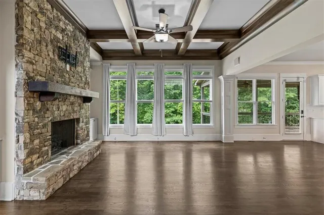 a view of an empty room with wooden floor fireplace and a window
