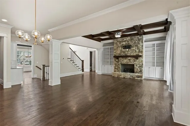 a view of an empty room with wooden floor fireplace and a window