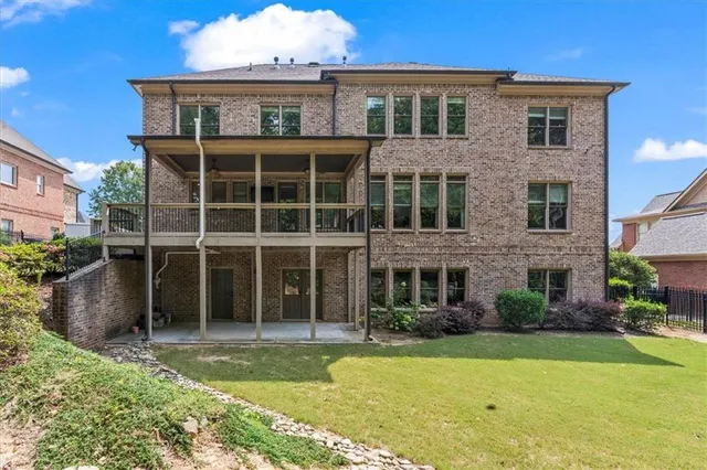 a view of a brick house with a yard plants and large tree