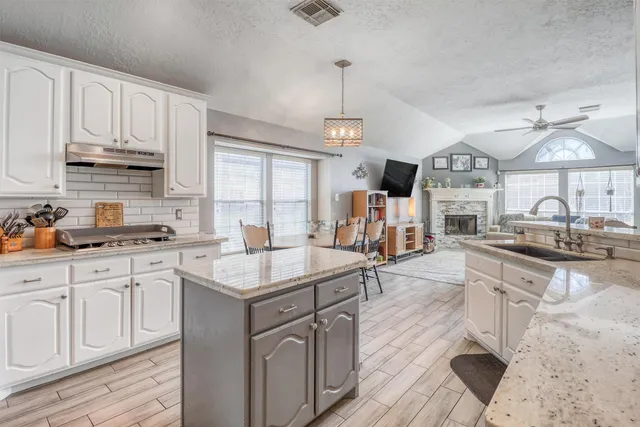 a kitchen with granite countertop a sink stove and cabinets
