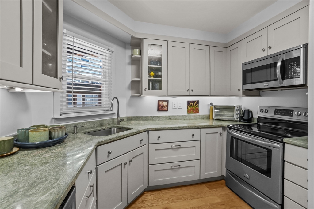 45 Main Street, Unit 112 Wareham, MA 02571 - Photo 11 of 30 a kitchen with granite countertop a sink stainless steel appliances and cabinets