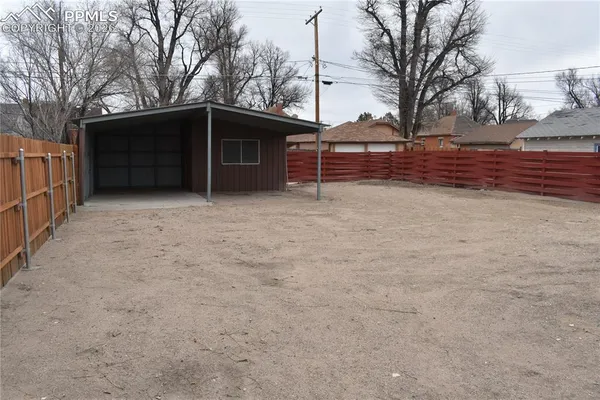 a view of backyard with wooden fence and large trees