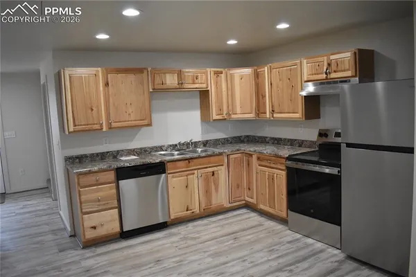 a kitchen with stainless steel appliances granite countertop a stove a sink and a refrigerator
