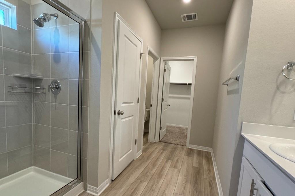 12604 Dairywork Road Buda, TX 78610 - Photo 9 of 20 A well-lit primary bathroom provides a spacious walk-in shower and ample vanity space.