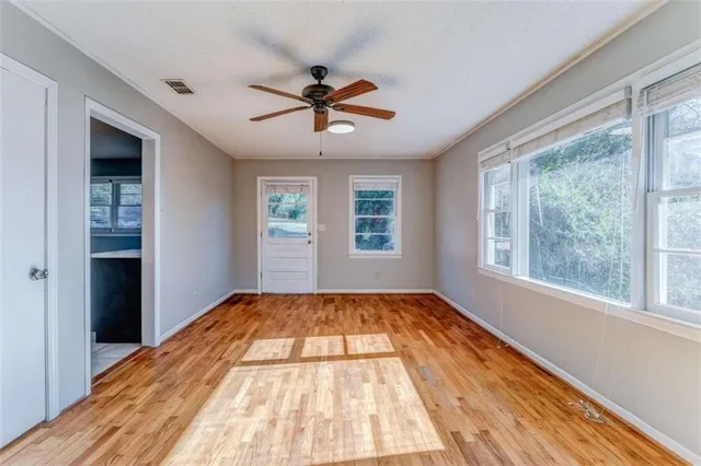 a view of empty room with wooden floor and fan