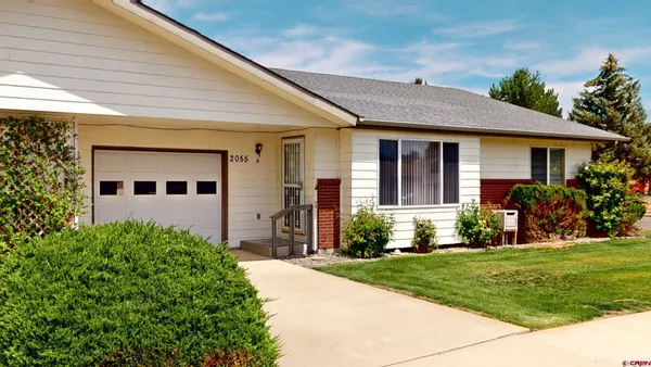 a front view of a house with a yard and potted plants
