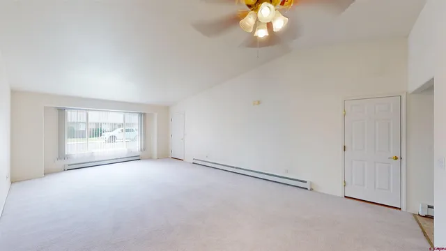 an empty room with chandelier fan and windows