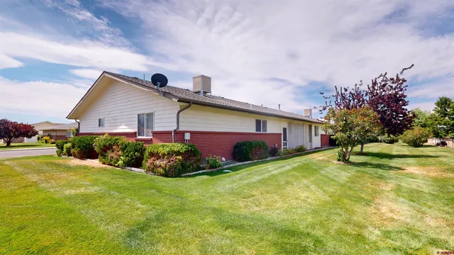 a front view of house with yard and trees in the background