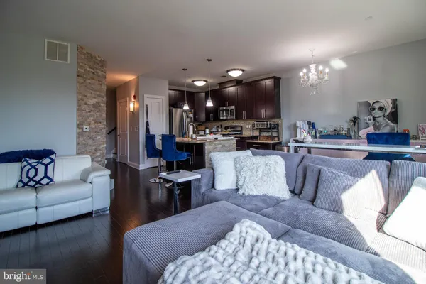 a living room with furniture a chandelier and kitchen view