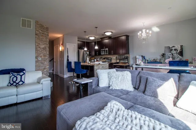 a living room with furniture a chandelier and kitchen view