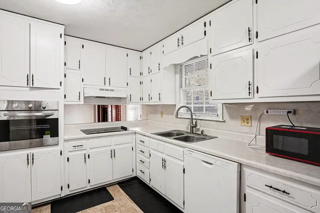 a kitchen with stainless steel appliances granite countertop white cabinets sink and stove