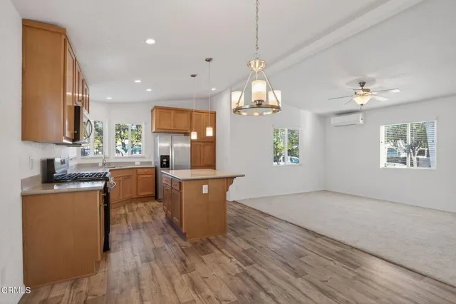 a large kitchen with kitchen island a sink dishwasher a stove a dining table and chairs with wooden floor