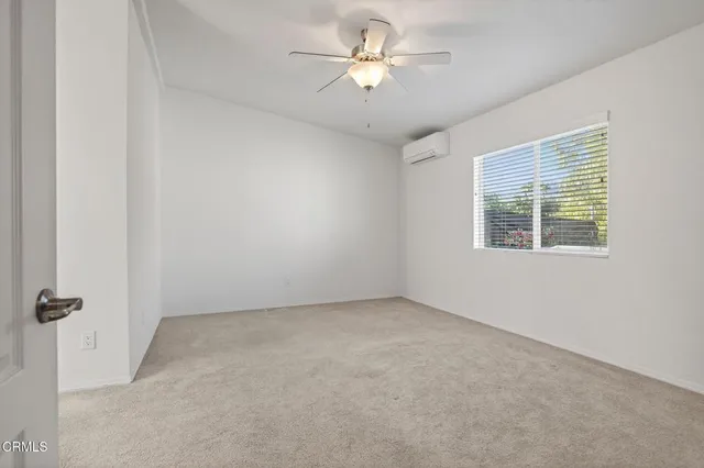 an empty room with a window and a fan