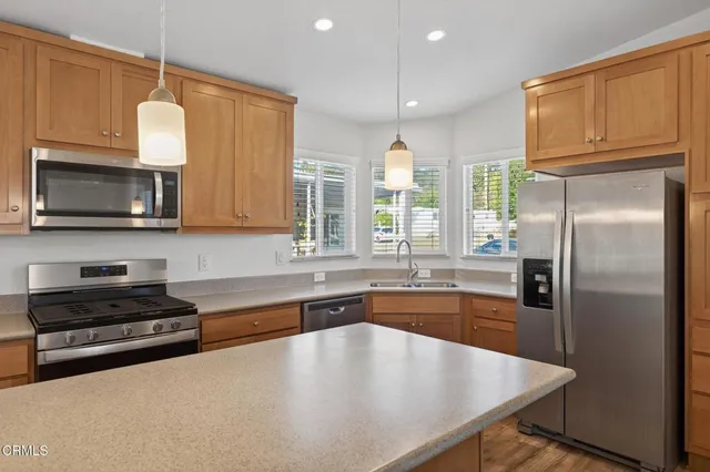 a kitchen with stainless steel appliances granite countertop a sink a microwave cabinets and a refrigerator
