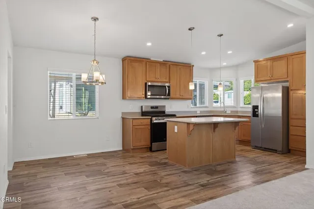 a kitchen with stainless steel appliances granite countertop a refrigerator a sink dishwasher a stove with wooden floor