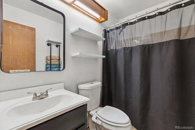 a bathroom with a sink a toilet a mirror and shower curtain