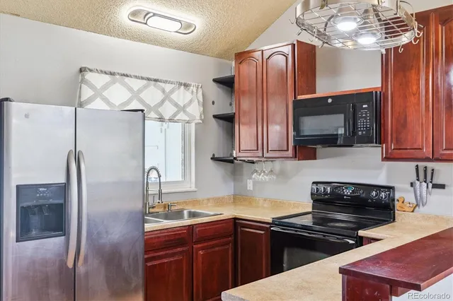 a kitchen with stainless steel appliances granite countertop a refrigerator a stove top oven a sink and dishwasher