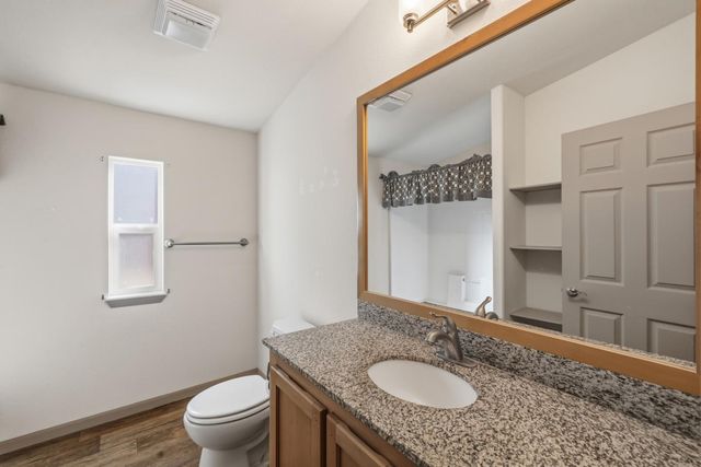 a bathroom with a granite countertop sink a toilet and a mirror