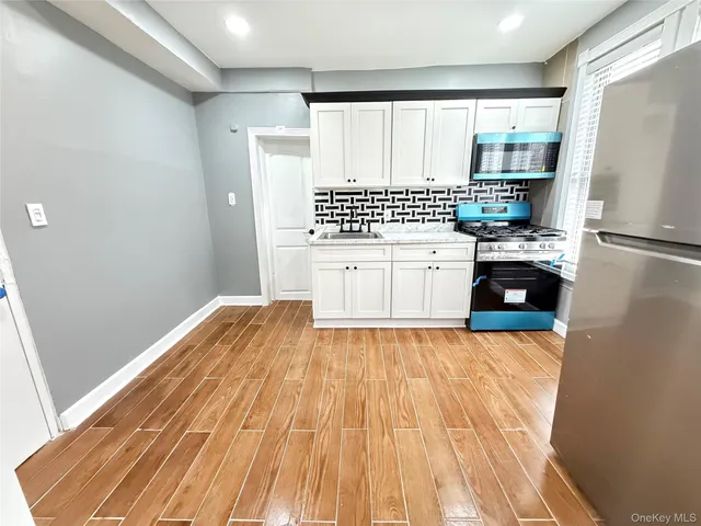 a kitchen with a refrigerator and white cabinets