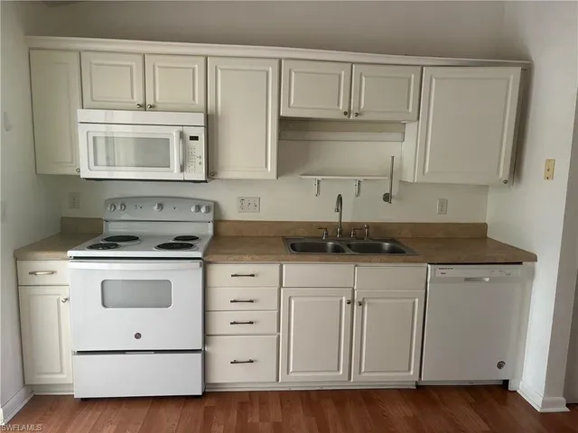 a kitchen with white cabinets and white appliances