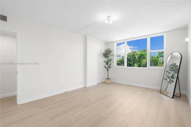 a view of an empty room with a window and wooden floor