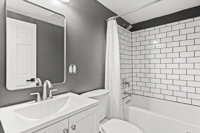 a bathroom with a bathtub shower sink vanity and toilet